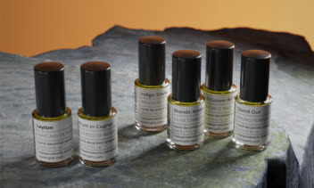 عکاسی تبلیغاتی و چیدمان هنری نمونه‌های عطر لوکس روی سطح سنگی